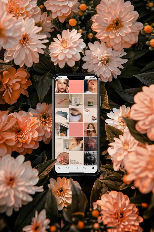 A phone showing a social media feed, held against a wall of peach flowers